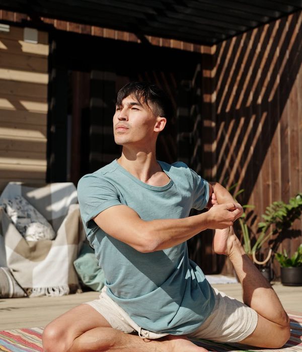 Silhouette of a man stretching against a calm, warm-toned background, suggesting well-being.